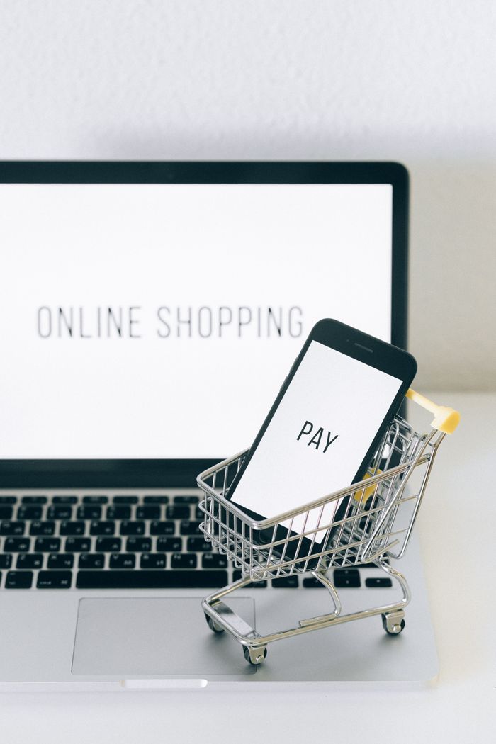mission-img A smartphone in a miniature cart on a laptop symbolizes online shopping and digital payment.